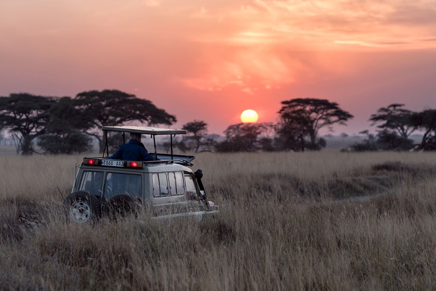 Open-roof Osuka Land Cruiser silhouetted against a Kenyan sunset